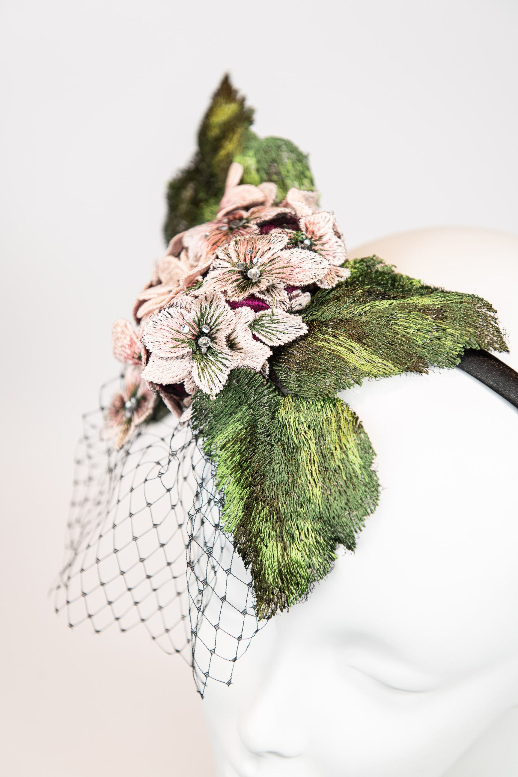 Fascinator headpiece with pink hydrangeas, large green leaves, and black birdcage netting