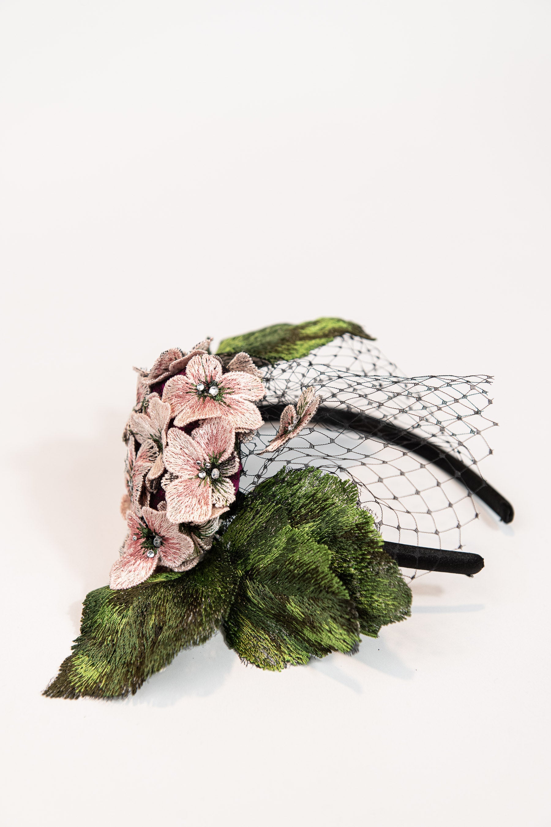 Fascinator headpiece with pink hydrangeas, large green leaves, and black birdcage netting